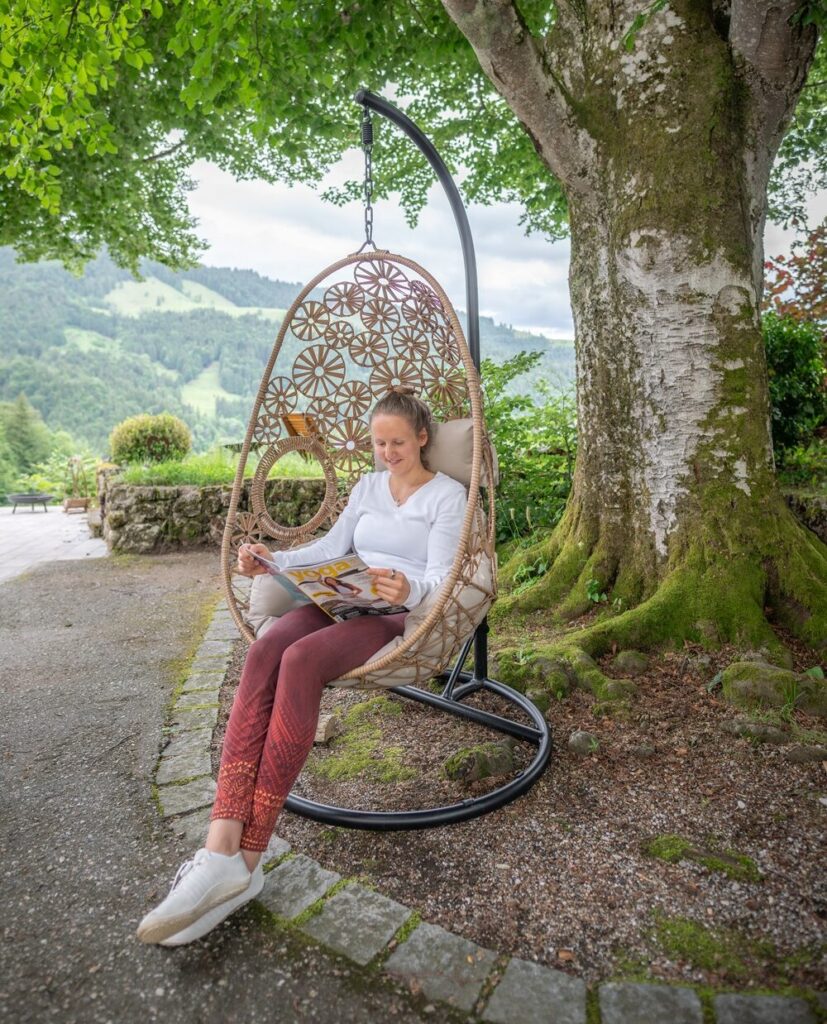 Frau liest in einem Hängesessel im Grünen