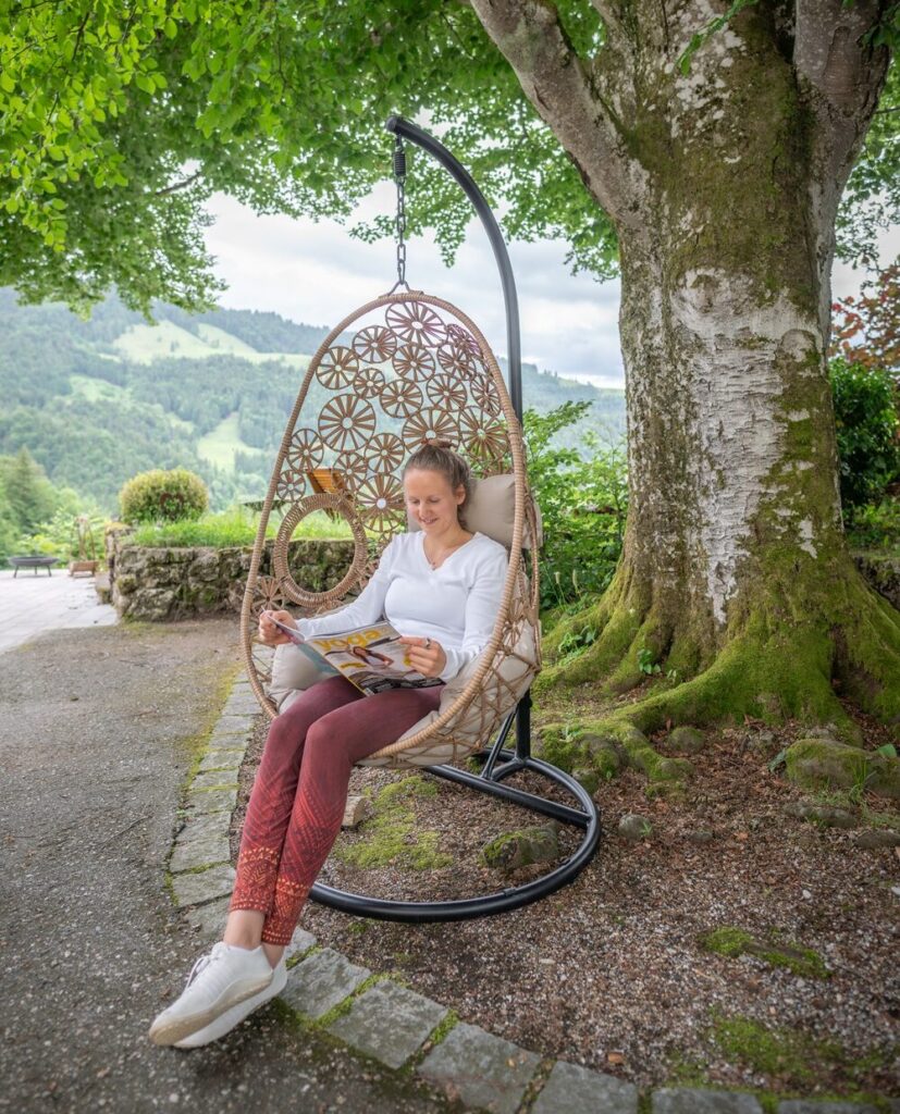 Frau liest in einem Hängesessel im Grünen