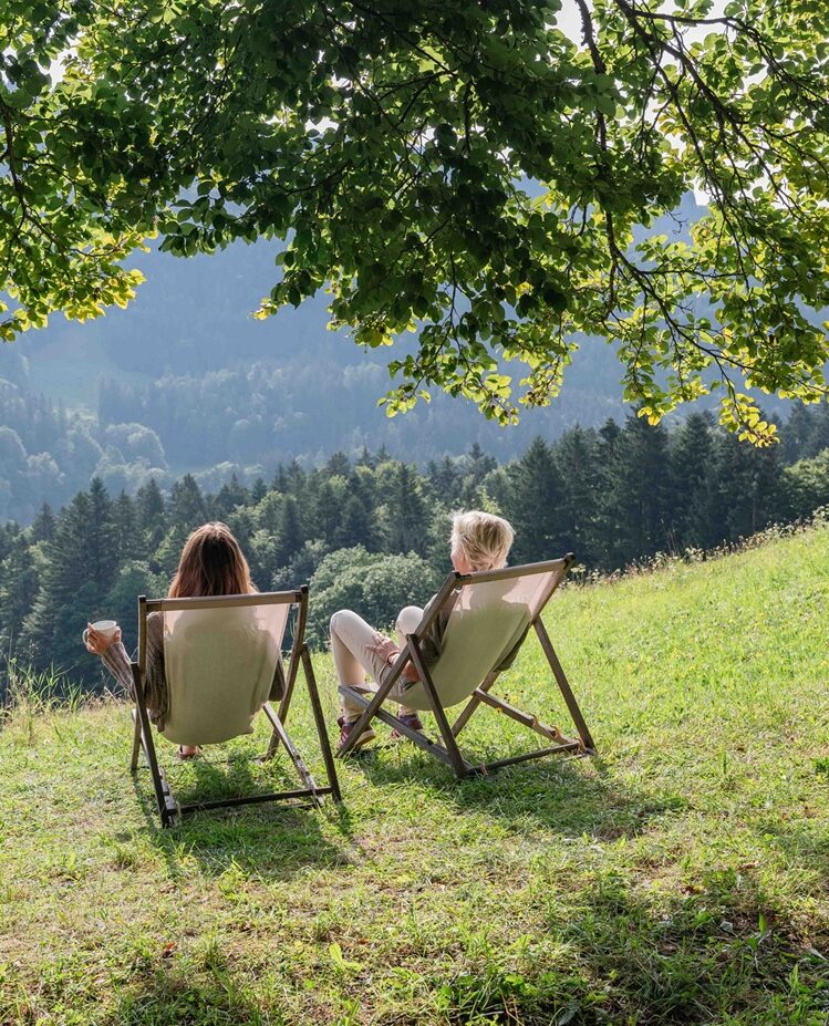 Gast sitzt allein mit Blick ins Tal, umgeben von Chiemgauer Landschaft