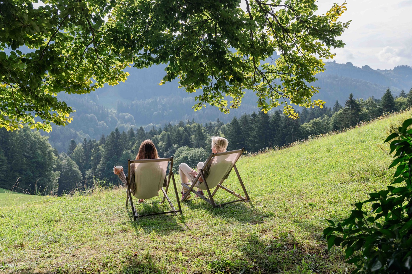 Gast sitzt allein mit Blick ins Tal, umgeben von Chiemgauer Landschaft
