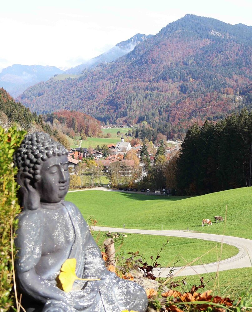 Buddha-Statue mit Blick auf eine herbstliche Berglandschaft