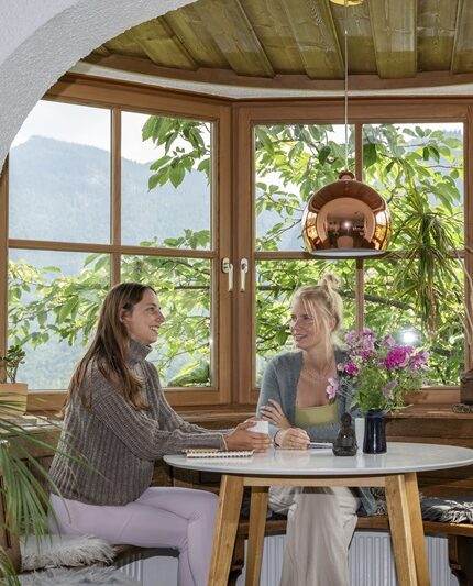 2 frauen sitzen drinnen und unterhalten sich