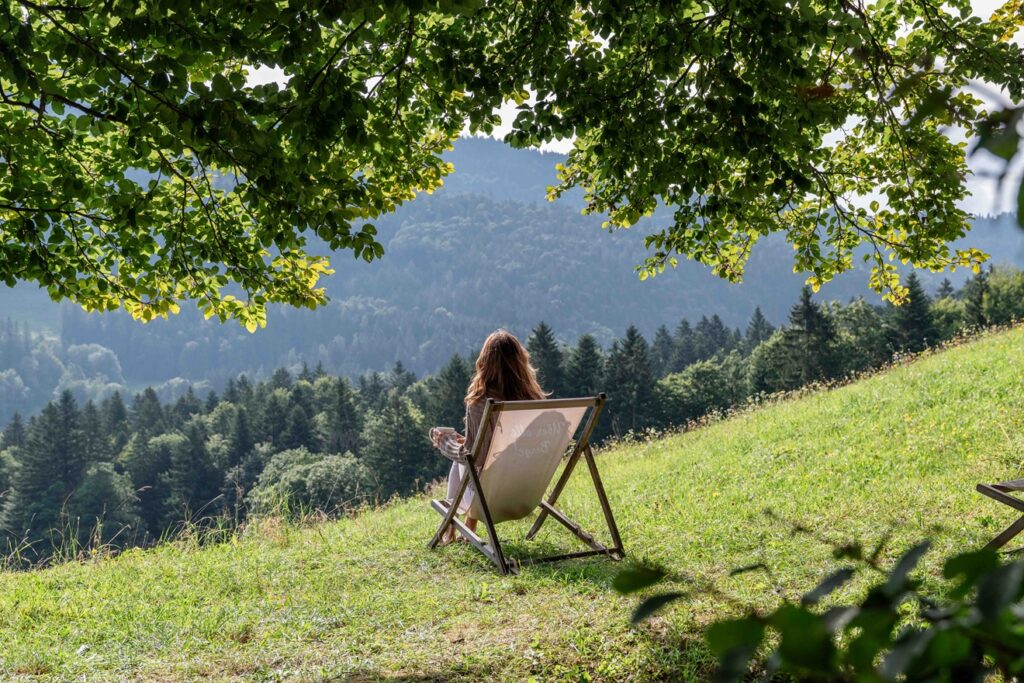 Person sitzt draußen mit Blick auf die Chiemgauer Berge
