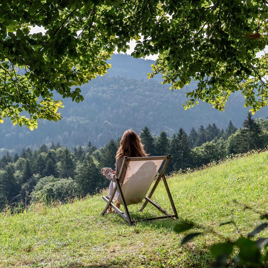 Person sitzt draußen mit Blick auf die Chiemgauer Berge