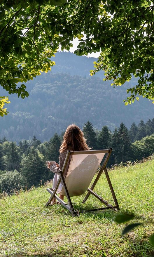 Person sitzt draußen mit Blick auf die Chiemgauer Berge