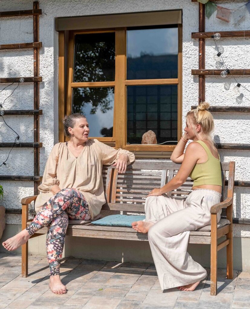 Zwei Frauen auf einer Bank draußen.
