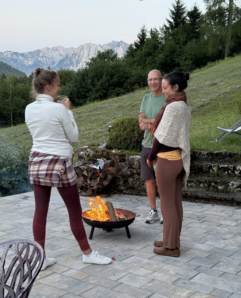 Drei Personen am Lagerfeuer draußen.