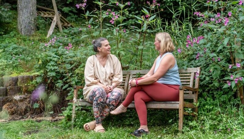 2 frauen im gespräch auf einer gartenbank