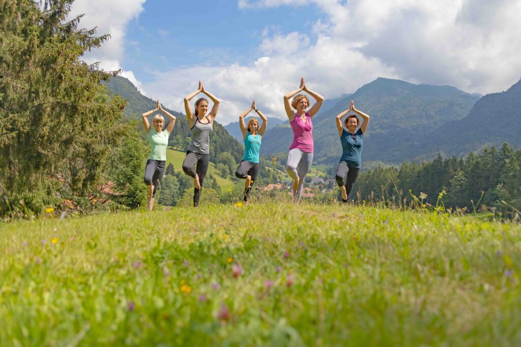 Yogagruppe in Baumstellung mit Alpenpanorama im Chiemgau